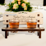 Charming personalized wedding gift featuring a wooden schnapps bench with engraved names, two shot glasses, and a heart cutout.