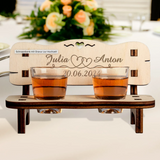 Charming personalized wedding gift featuring a wooden schnapps bench with engraved names, two shot glasses, and a heart cutout.