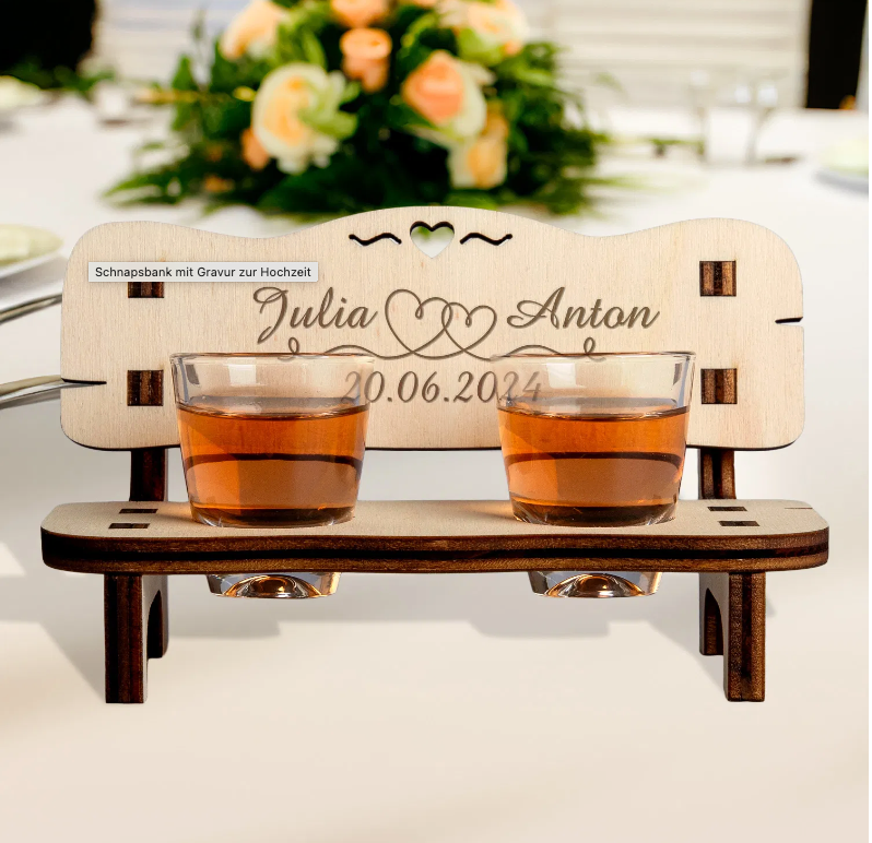 Charming personalized wedding gift featuring a wooden schnapps bench with engraved names, two shot glasses, and a heart cutout.