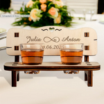 Charming personalized wedding gift: a wooden schnapps bench with engraved names and date, featuring two shot glasses and a heart cutout.