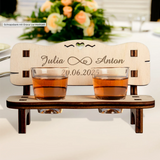Charming personalized wedding gift: a wooden schnapps bench with engraved names and date, featuring two shot glasses and a heart cutout.
