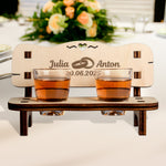 Charming personalized wedding gift - a wooden schnapps bench with engraved names and date, featuring two shot glasses and a heart cutout.